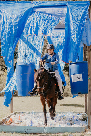 Image of a retreat participant confidently guiding her horse through an obstacle, demonstrating skill and partnership during the retreat activities.