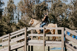 A customer confidently crossing a bridge in the obstacle course during a Horse Help retreat, building trust and overcoming challenges with their horse.