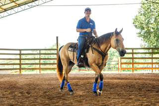 Image of Michael Gascon striking a pose with a horse in the arena, showcasing the MG sport boots, highlighting both equestrian style and the importance of protective gear during training sessions.