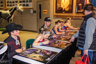 Image of Kelsey Gascon, alongside other participants of the Gascon Horsemanship Never Give Up Tour, engaging in autograph signing, capturing a moment of connection and appreciation with the audience.