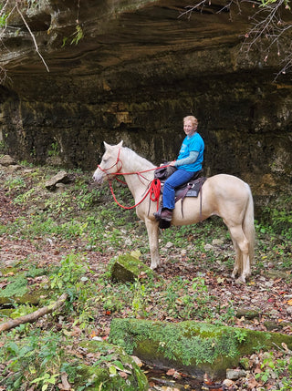 Image of a retreat participant enjoying a trail ride with her horse, experiencing the beauty of nature and the bond between rider and horse during the retreat.
