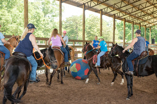 Image of retreat participants enjoying a game of horse soccer in the arena, fostering camaraderie and equestrian fun during the retreat.