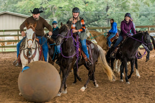 Energetic scene of multiple retreat participants having fun playing horse soccer during the Horse Help Retreat, fostering camaraderie and enjoyment in the equestrian community.