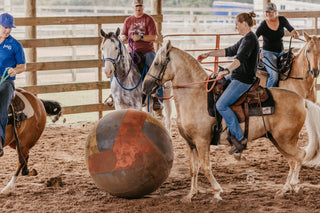 Image of Michael Gascon and retreat participants enjoying a game of horse soccer in the arena, fostering camaraderie and equestrian fun during the retreat.