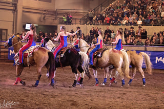 Image featuring Kelsey Gascon and the Trixie Chicks Riders during a performance, showcasing extraordinary equestrian skills and thrilling tricks. Witness the excitement of skilled horsemanship and dazzling tricks in action.