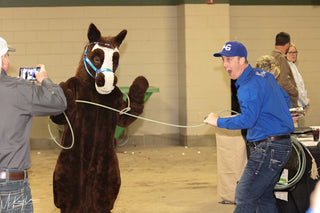 Image of Michael Gascon posing with a horse mascot during the Gascon Horsemanship Never Give Up Tour, capturing a playful and spirited moment that adds fun to the tour experience.