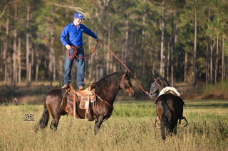 Michael Gascon showcasing incredible horsemanship skills by standing atop one horse while skillfully guiding another horse. A remarkable display of balance, control, and a deep connection with the animals.