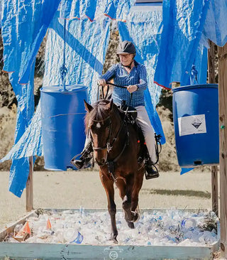 Image of a retreat participant confidently guiding her horse through an obstacle, demonstrating skill and partnership during the retreat activities.