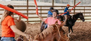 Image of retreat participants joyfully engaging in jousting activities in the arena, creating a lively and spirited atmosphere during the retreat experience.
