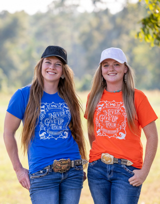 Kelsey Gascon and a member of the Horse Help staff proudly display MG caps and Horse Help unisex shirts featuring the Never Give Up tour logo.