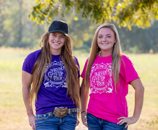 Kelsey Gascon and a member of the Horse Help staff proudly display MG caps and Horse Help unisex shirts featuring the Never Give Up tour logo.